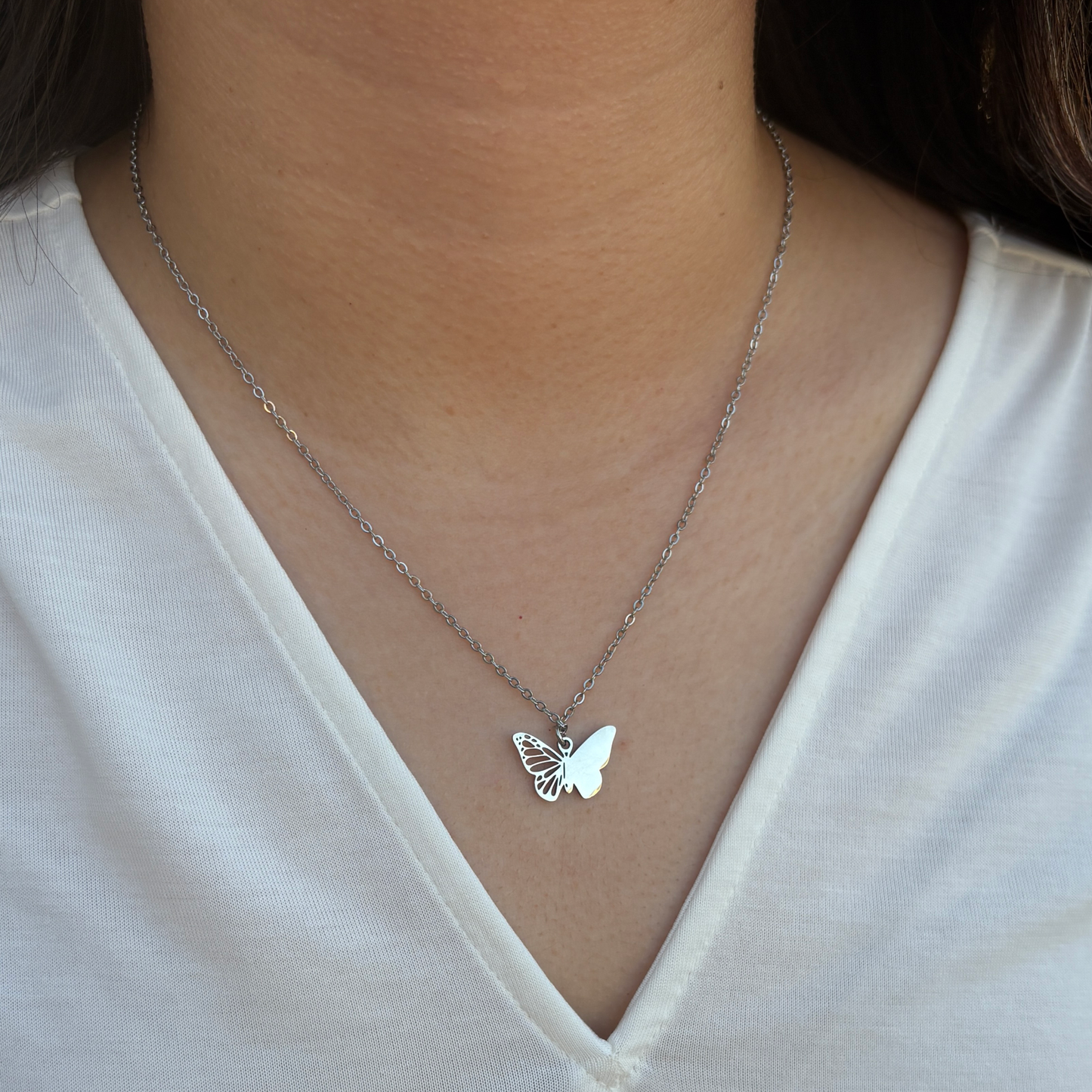 Silver filigree butterfly charm necklace worn by a woman