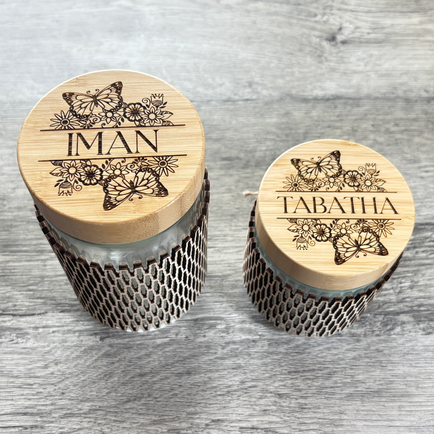 Top view of a 24oz and a 16oz glass jar that have custom engraving on bamboo lid and a wooden sleeve.