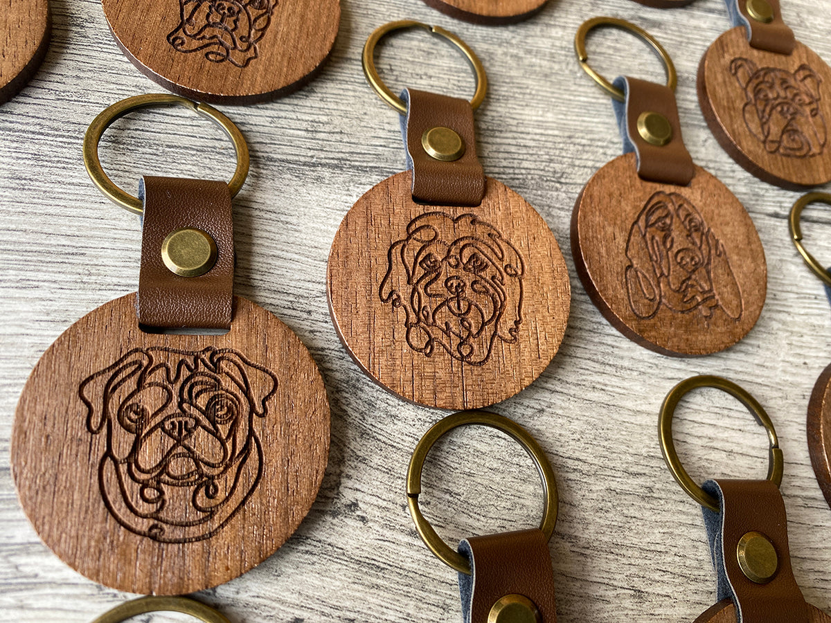 Laser-engraved pet keychains featuring your favorite dog breed, made from walnut wood with a brass key ring.