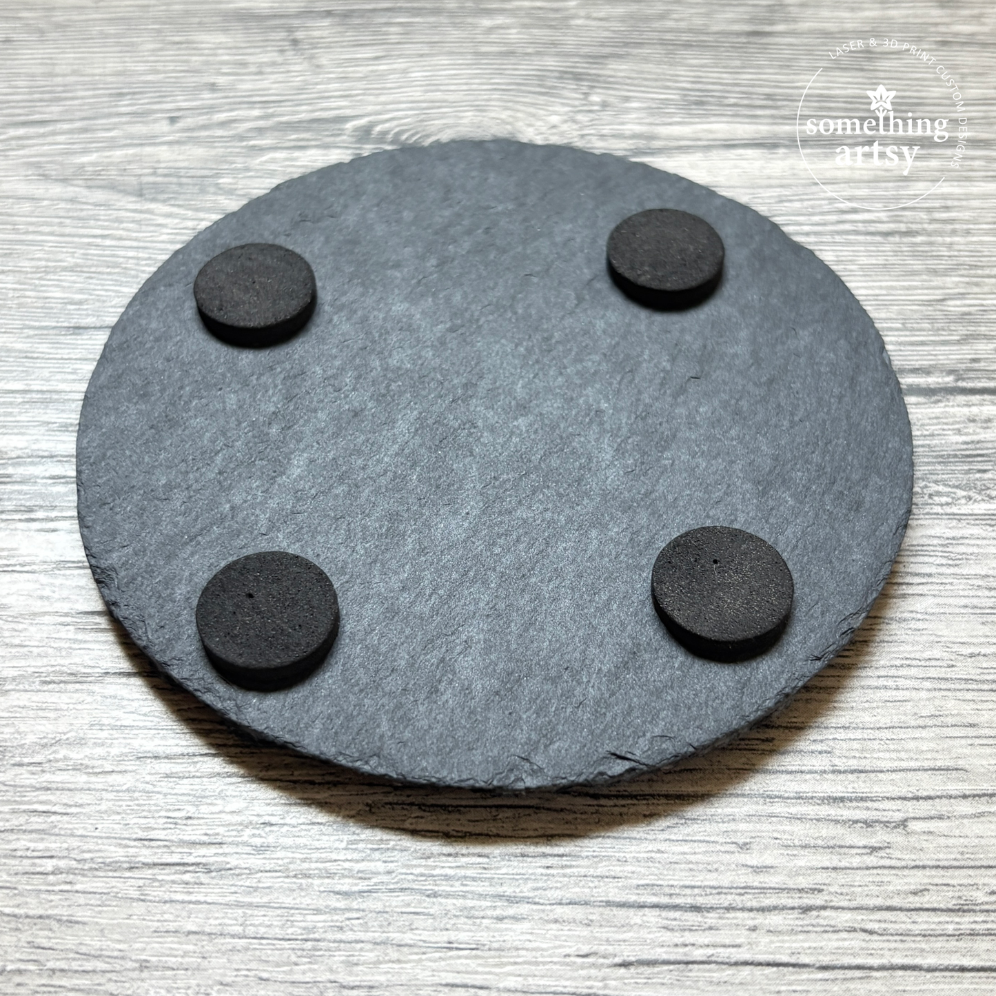 Back of a round slate coaster showing the pads underneath
