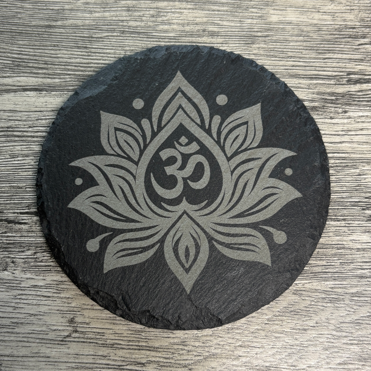 round slate coaster with an engraved om symbol