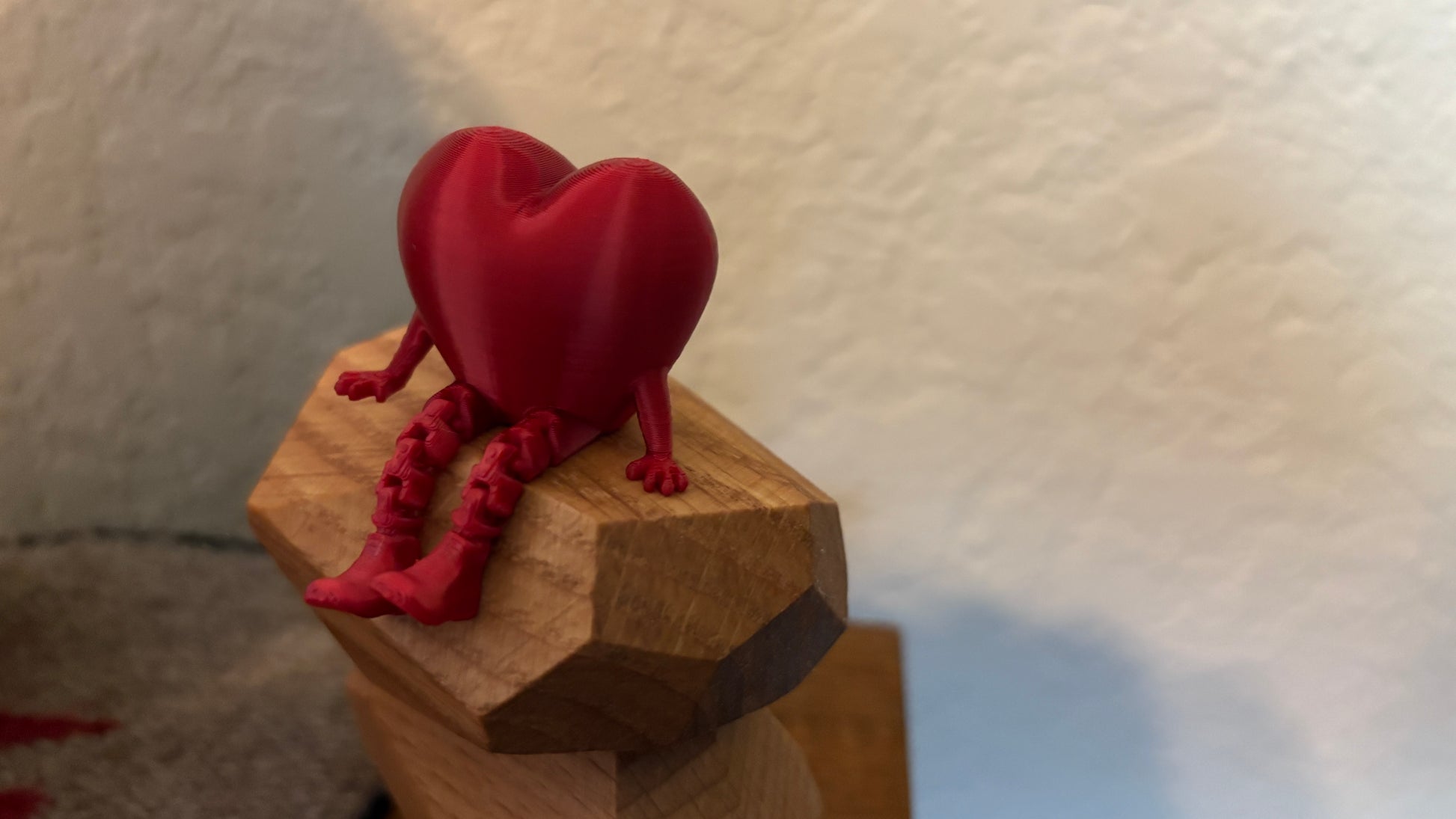3D printed articulating heart figure sitting on top of a wooden pieces
