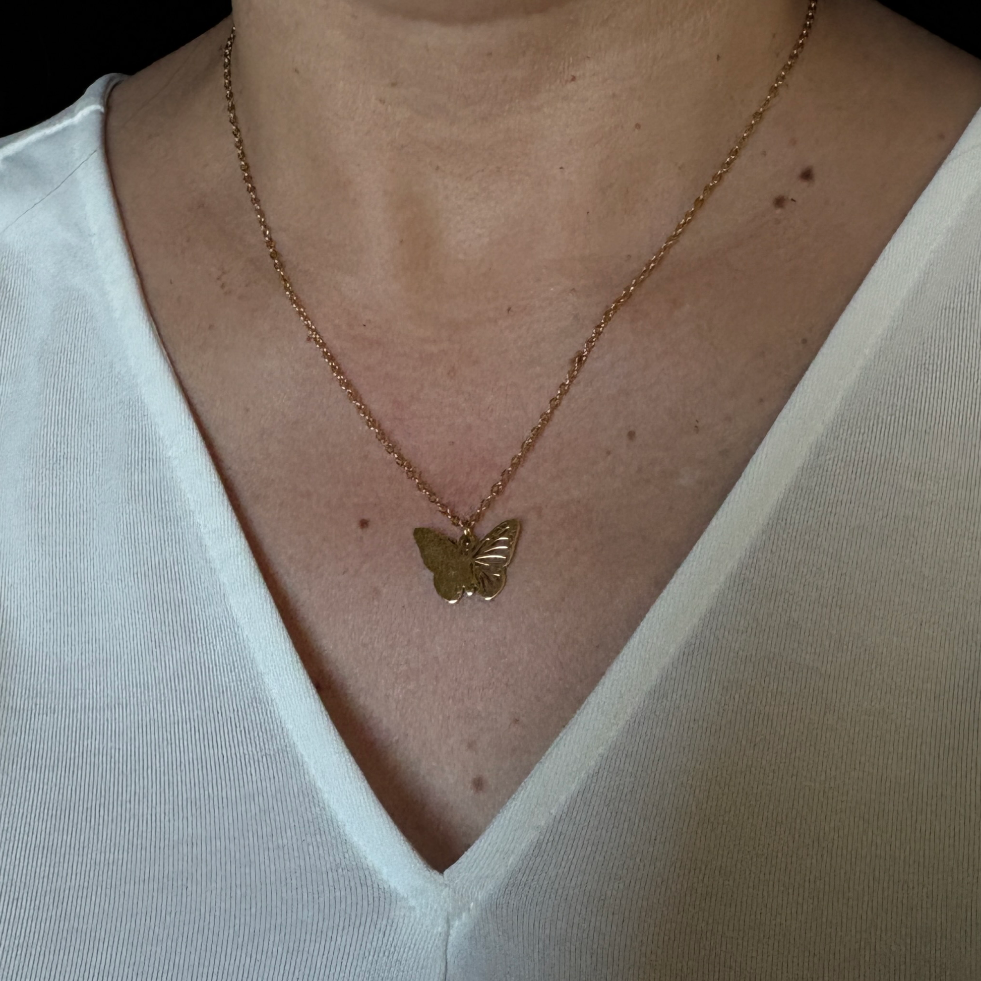 Gold filigree butterfly charm necklace  worn by a woman