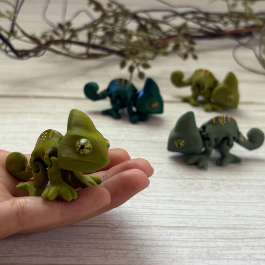 Colorful 3D printed articulated chameleon with flexible joints, posed on a hand.