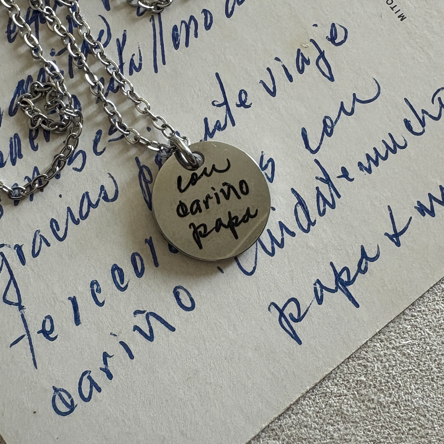 15mm silver disk necklace with a handwritten custom engraving. Sitting above the letter with the words that were used for the engraving.