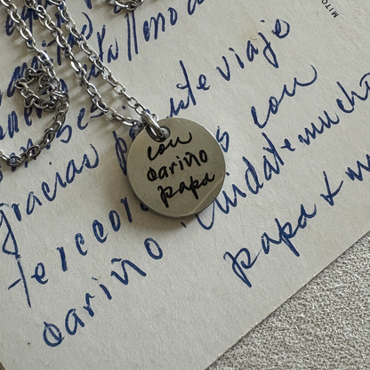 15mm silver disk necklace with a handwritten custom engraving. Sitting above the letter with the words that were used for the engraving.