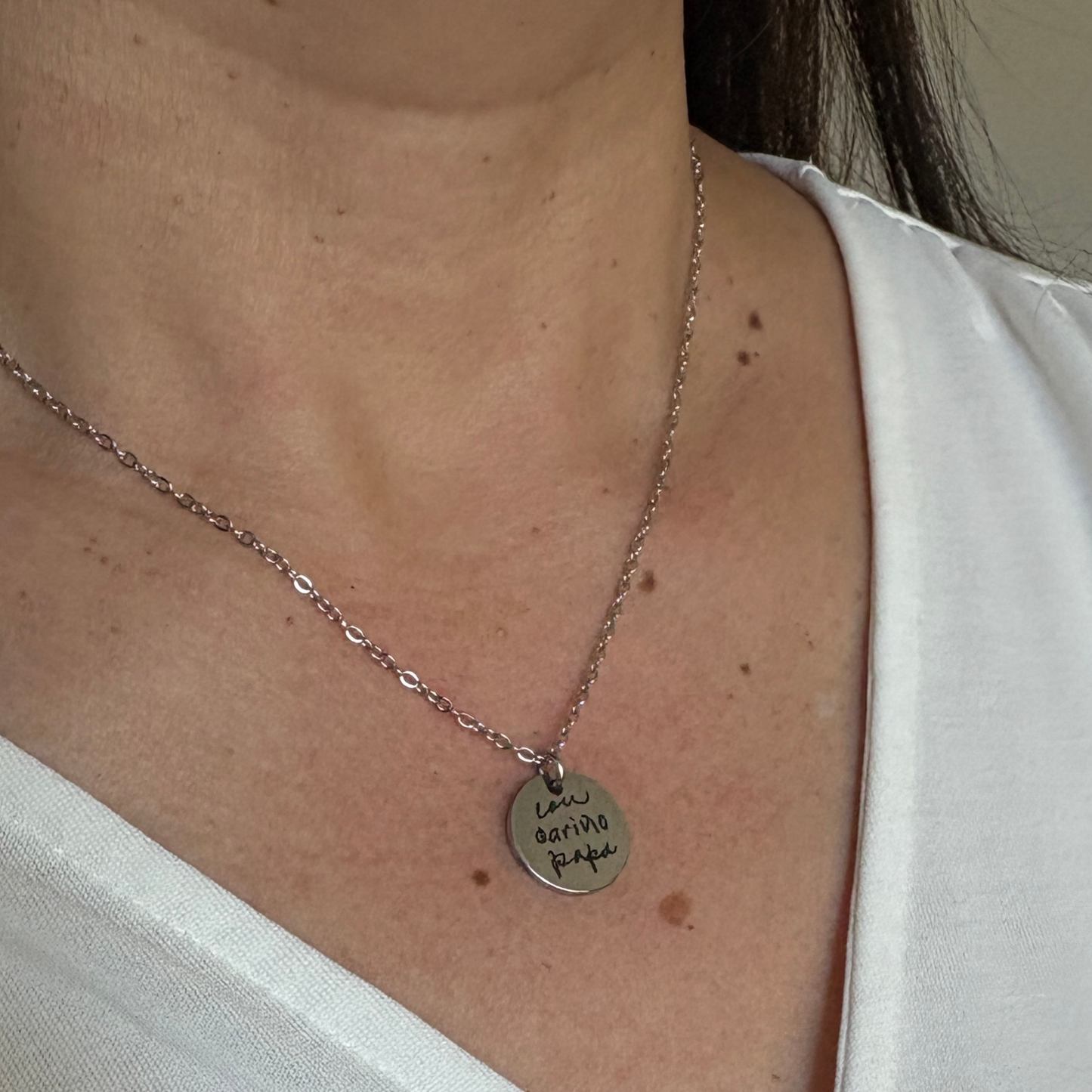 15mm silver disk necklace that has a custom handwritten engraving being worn by a woman.
