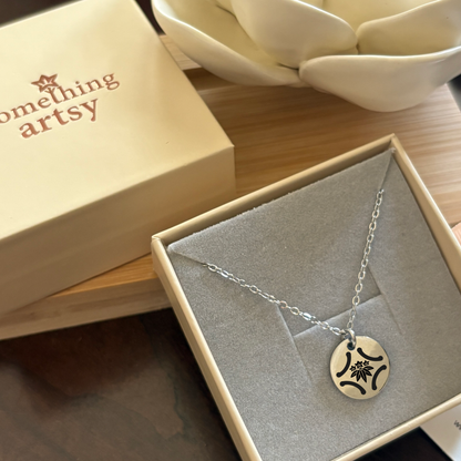 Jewelry box that holds a 15 mm silver disk necklace with a custom engraving.