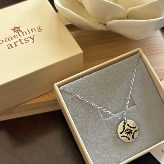 Jewelry box that holds a 15 mm silver disk necklace with a custom engraving.