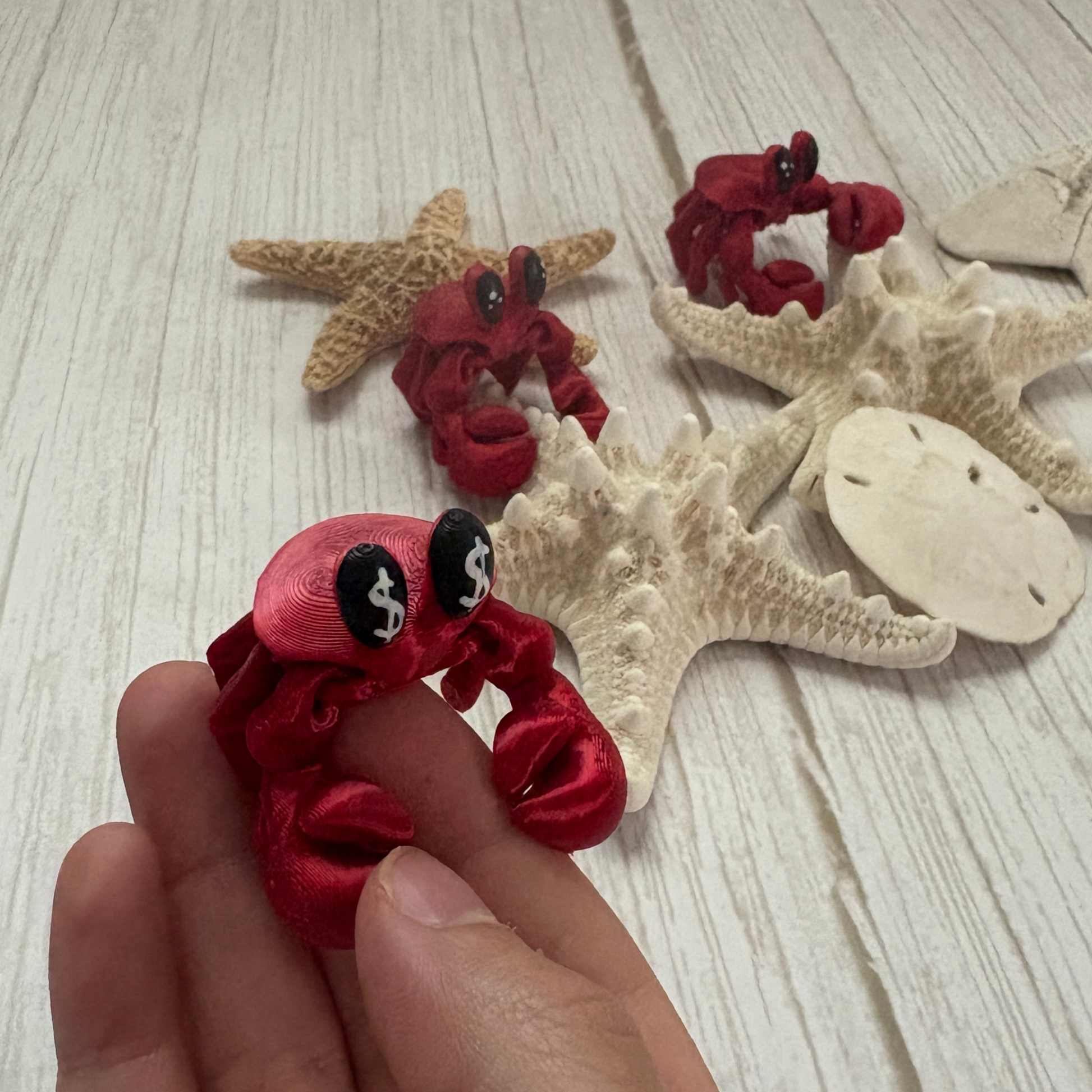 3D printed articulating crab held by a hand to show size