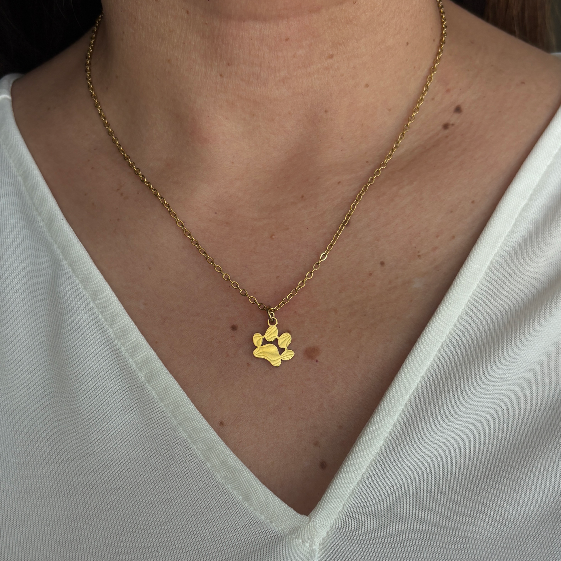 The gold paw necklace in display with someone wearing it