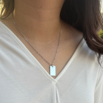 Woman wearing a silver rounded rectangle with a white shirt