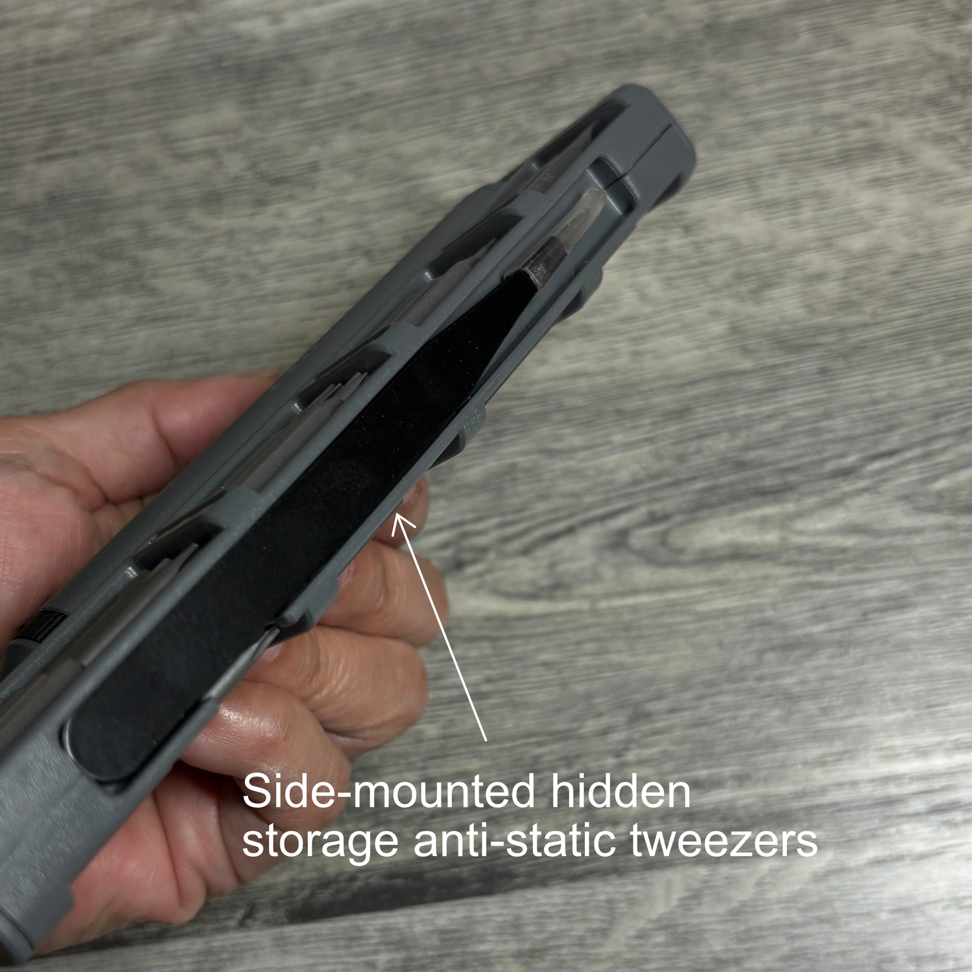 Hand holding the electric screwdriver case with side-mounted hidden storage anti-static tweezers.