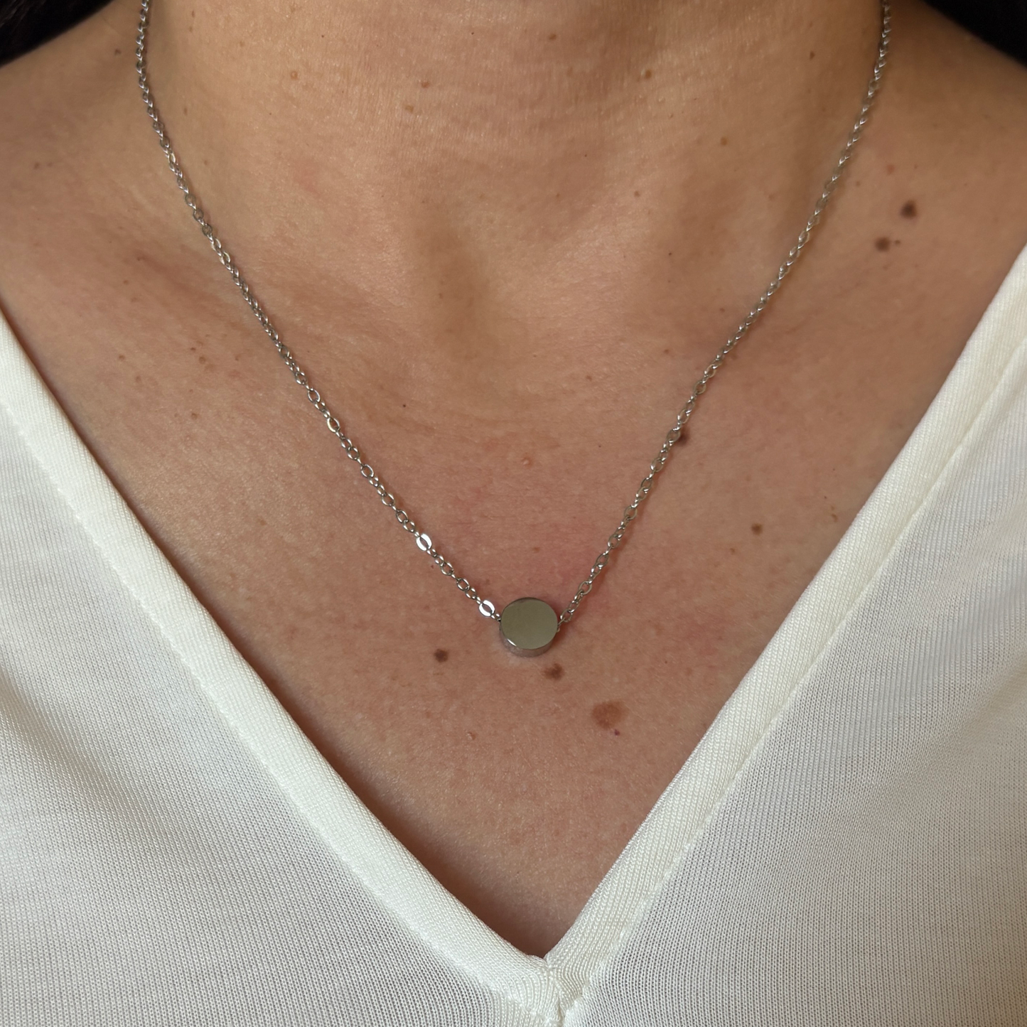Woman wearing a stainless steel tiny circle charm  with silver finish.