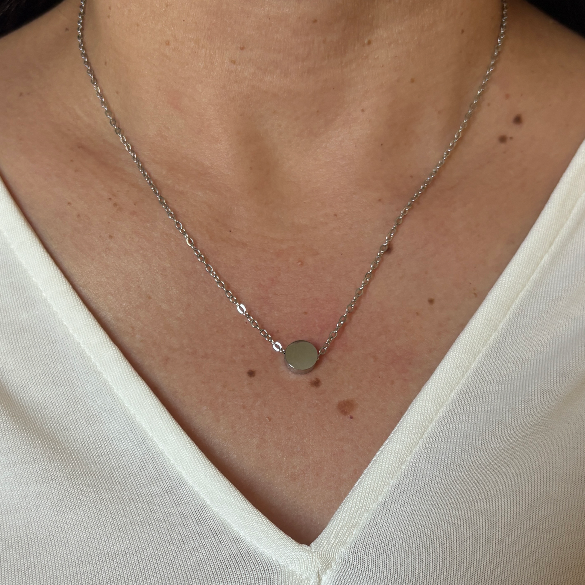 Woman wearing a stainless steel tiny circle charm  with silver finish.