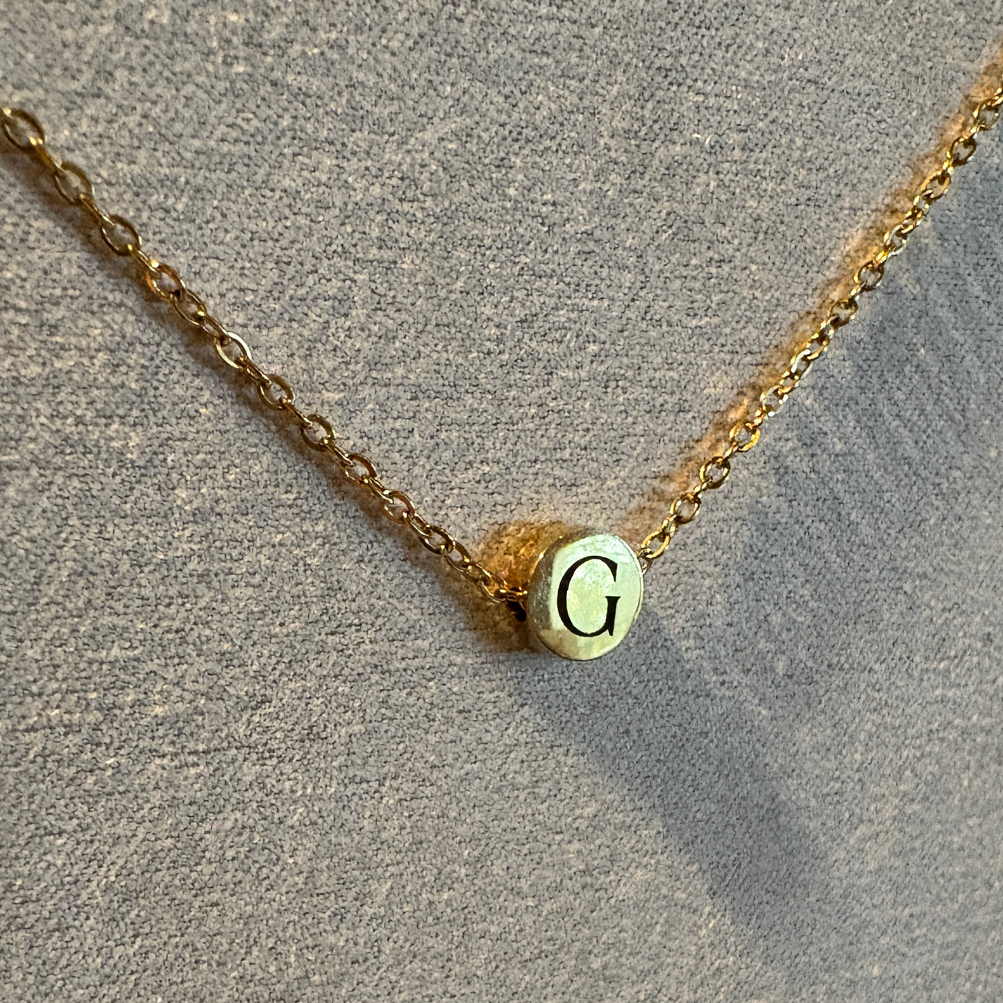 Tiny circle charm necklace with a gold finish that has a custom engraved initial "G".
